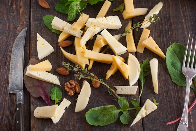 Varietà di formaggio con coltello e forchetta su sfondo di legno scuro Bellissimo ristorante con sfondo spuntino per il concetto di vino