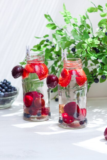 Varietà di frutta con acqua detox in bottigliette di vetro. Bevande estive rinfrescanti. Concetto di dieta sana.