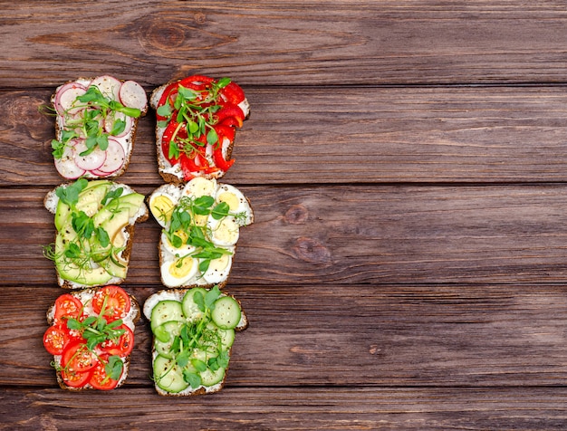 Varietà di mini panini con crema di formaggio e verdure su una superficie di legno