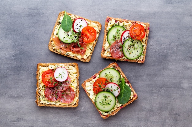 Varietà di mini panini con crema di formaggio, verdure e salame