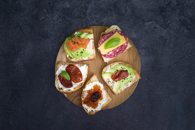 Varietà di panini di tapas per aperitivo su legno su sfondo nero Vista dall'alto