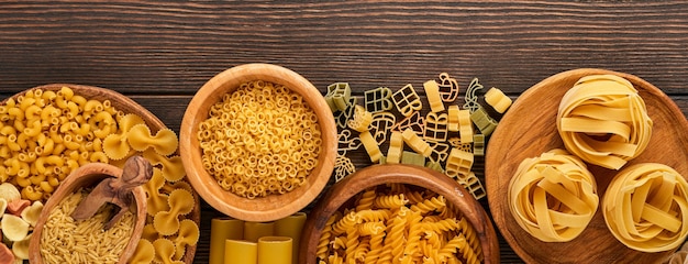 Varietà di pasta italiana tradizionale: spaghetti variopinti, tagliatelle, farfalle, penne, ptititm, tagliatella, fusilli, cannelloni