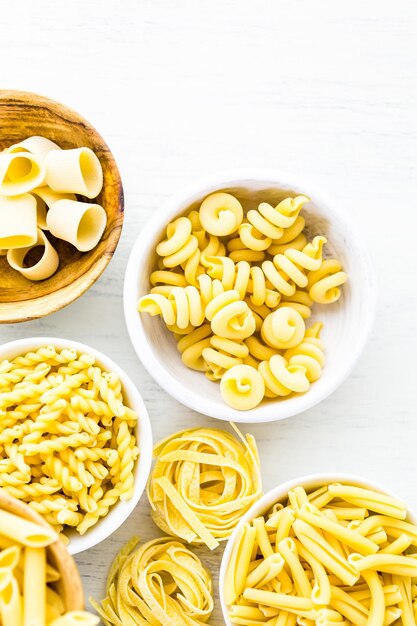 Varietà di pasta secca gialla in piccole ciotole rotonde.