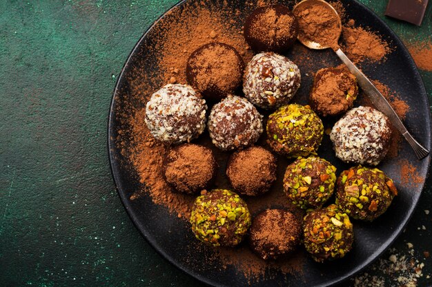 Varietà di tartufi di cioccolato fondente fatti in casa con cacao in polvere, pistacchi, mandorle