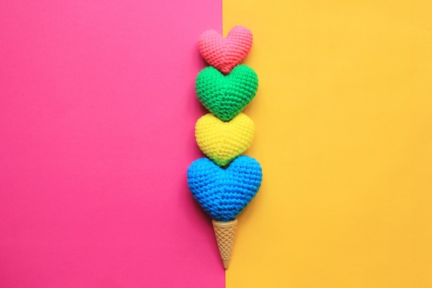 Variopinto del cuore fatto a mano all'uncinetto in tazza della cialda su fondo giallo e rosa per il giorno di biglietti di S. Valentino