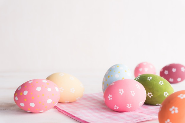 Variopinto delle uova di Pasqua con cheesecloth rosa e bianca su fondo di legno.