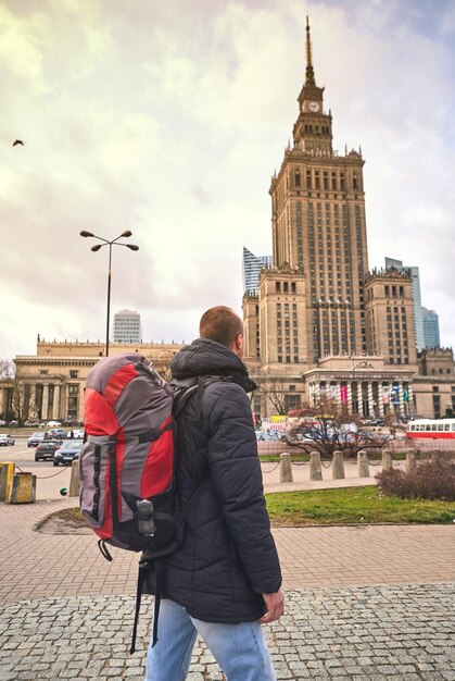 Varsavia Polonia 08 dicembre 2018 Giovane turista maschio che cammina per la città e guarda il Palazzo della Cultura e della Scienza a Varsavia Trascorrendo una felice vacanza in Polonia