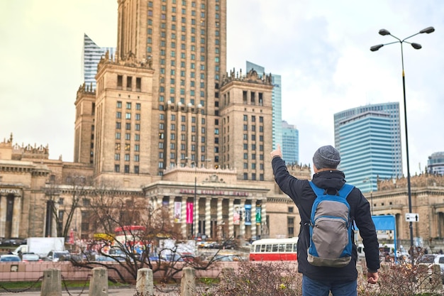 Varsavia Polonia 08 dicembre 2018 Giovane turista maschio che cammina per la città e guarda il Palazzo della Cultura e della Scienza a Varsavia Trascorrendo una felice vacanza in Polonia