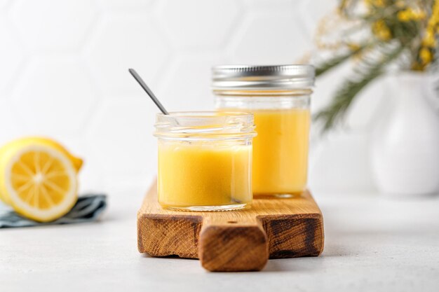 Vasetti con lemon curd Dessert al limone su tavola di legno con cucchiaio e mimosa