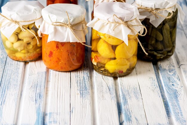 Vasetti di gustose verdure in salamoia Cibo in scatola fatto in casa Blu e bianco sullo sfondo di legno