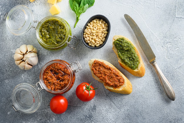 Vasetti di vetro con pesto rosso e verde e panini con salsa.