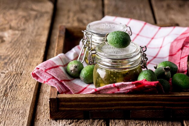 Vasetti di vetro di gustosa marmellata di Feijoa fatta in casa sul vassoio di legno Tovagliolo di sfondo Dessert orizzontale