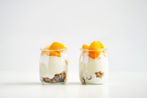 Vasetti simmetrici di yogurt greco con muesli e albicocche in scatola