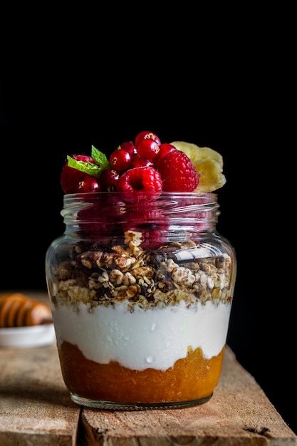 Vasetto di muesli fatto in casa con yogurt, marmellata di albicocche fatta in casa e lamponi