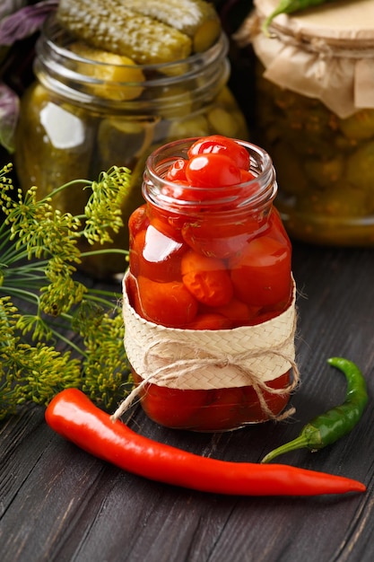 Vasi con conserve di pomodori e cetrioli su sfondo di legno