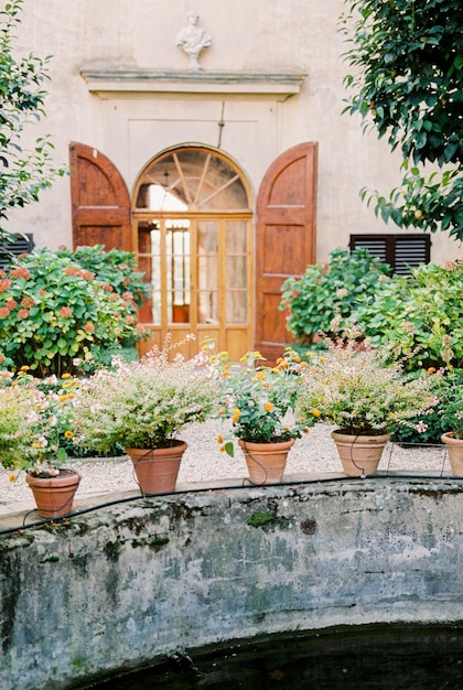 Vasi fioriti si trovano su un recinto di pietra vicino a una vecchia villa