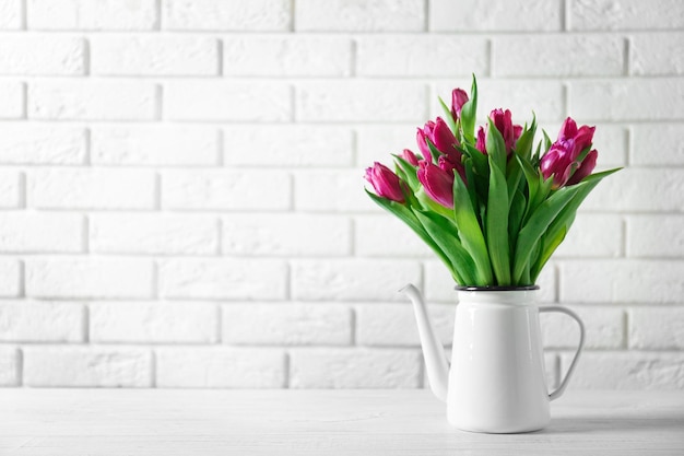 Vaso con bouquet di bellissimi tulipani su sfondo muro di mattoni