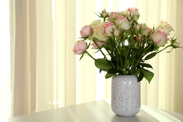 Vaso con bouquet di rose sul tavolo bianco