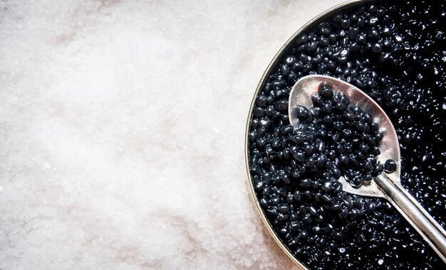 Vaso con caviale nero e un cucchiaio di sale. Spazio libero per il testo. Vista dall'alto