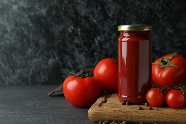 Vaso con concentrato di pomodoro e pomodori sulla tavola di legno