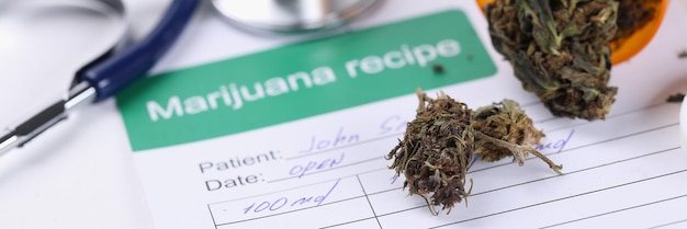 Vaso con foglie di marijuana essiccate e ricetta sdraiata sul primo piano del tavolo del medico