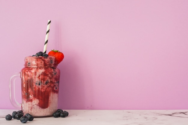 Vaso con fragole e mirtilli frullato con paglia