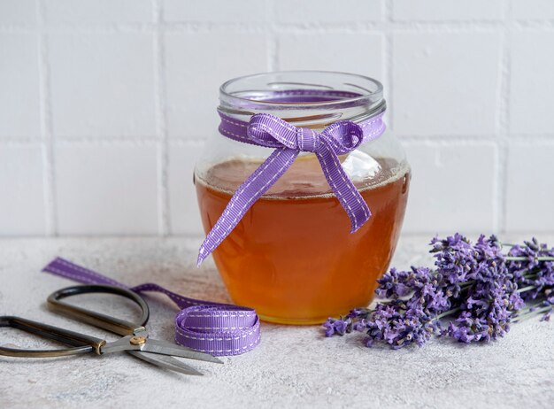 Vaso con miele e fiori di lavanda fresca su fondo di cemento