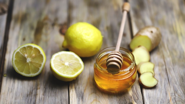 vaso con miele sul tavolo con zenzero e limoni accanto