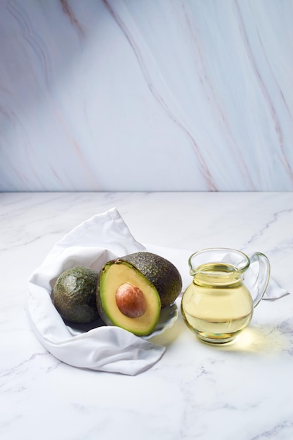 Vaso con olio e avocado fresco maturo sul tavolo