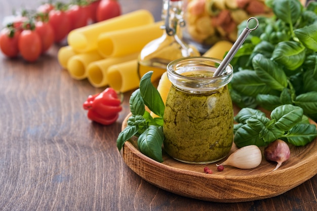 Vaso con pesto fatto in casa su fondo rustico con parmigiano, olio d'oliva, pesto di salsa, basilico e aglio