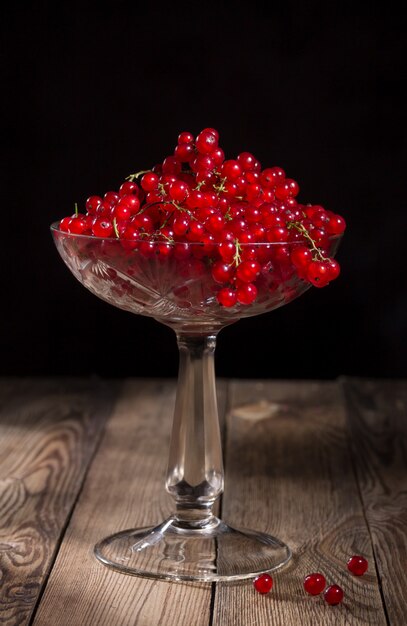 Vaso con ribes rosso su un tavolo di legno.