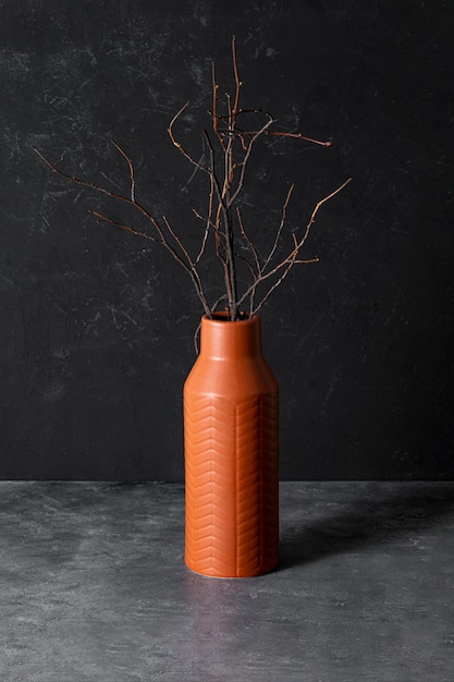 Vaso di argilla con rami secchi neri su uno sfondo nero Bouquet d'autunno eco-friendly concept card verticale cupo