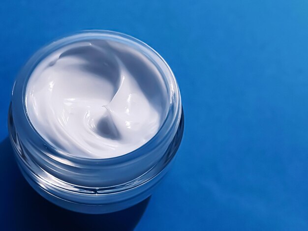 Vaso di crema idratante per il viso come campione di prodotto su sfondo blu scienza cosmetica di bellezza e cura della pelle
