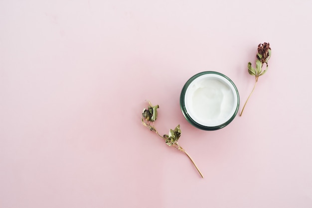 Vaso di crema idratante su uno sfondo rosa con spazio di copia. Il concetto di cura della pelle, idratazione, nutrizione e ingredienti naturali