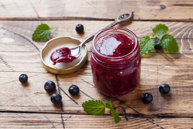 Vaso di marmellata di mirtilli fatta in casa su un fondo di legno.