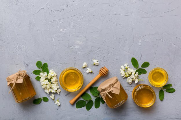 Vaso di miele con fiori di acacia e foglie di miele fresco vista dall'alto piatto