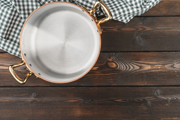 Vaso di rame con la tovaglia chekered sulla tavola di legno