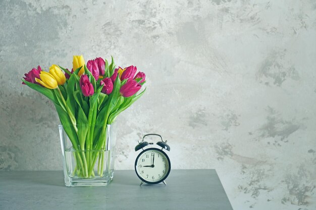 Vaso di vetro con bouquet di bellissimi tulipani su sfondo colorato