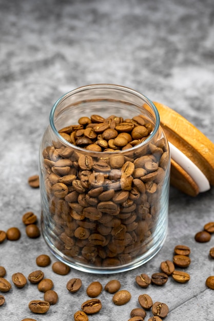 Vaso di vetro con chicchi di caffè su sfondo scuro Primo piano di caffè