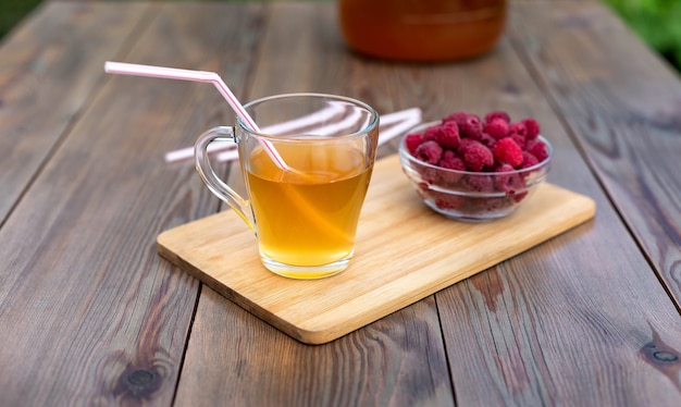 Vaso di vetro con Kombucha Vetro versato con Kombucha e lamponi nel giardino estivo summer