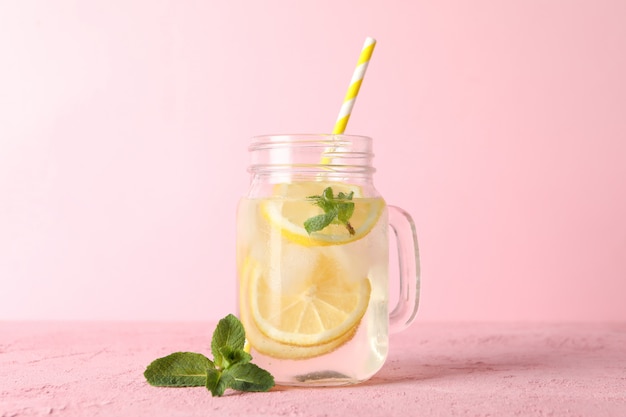 Vaso di vetro con limonata sulla superficie rosa. Bevanda fresca