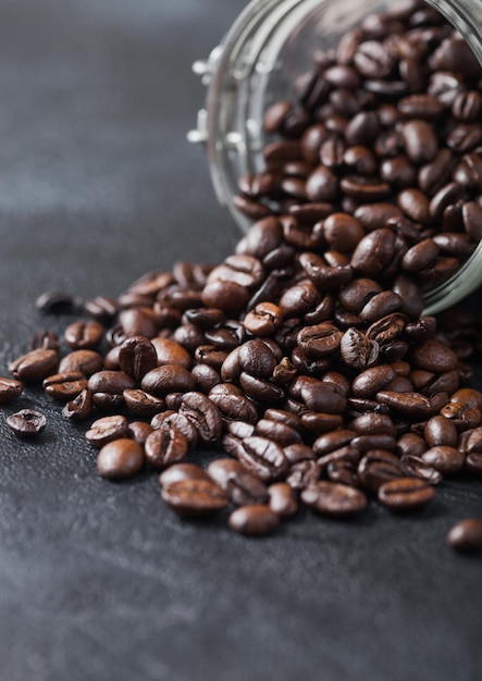 Vaso di vetro di chicchi di caffè organici crudi freschi su sfondo nero Macro