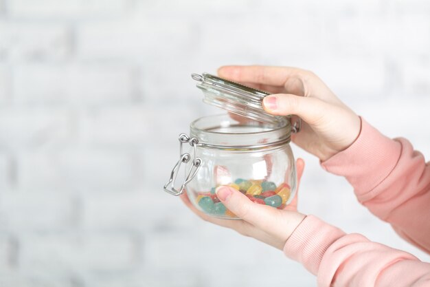 Vaso di vetro di detenzione femminile pieno di jelly bean