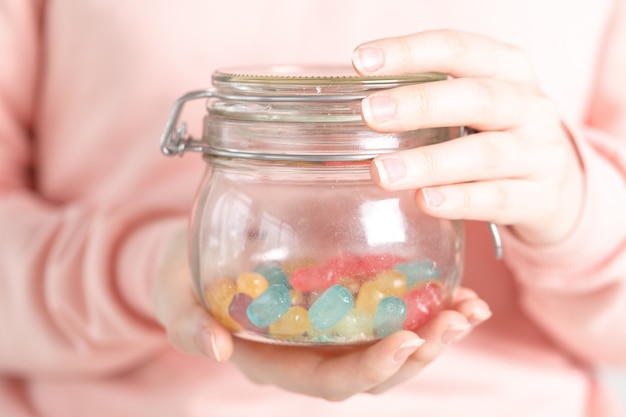 Vaso di vetro di detenzione femminile pieno di jelly bean