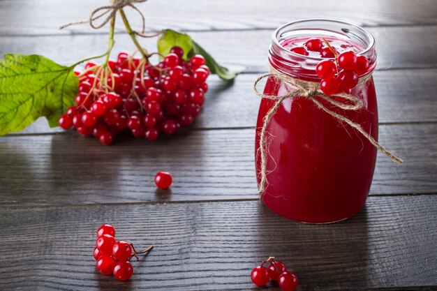 Vaso di vetro di marmellata fatta in casa di viburno con bacche fresche sul tavolo scuro.