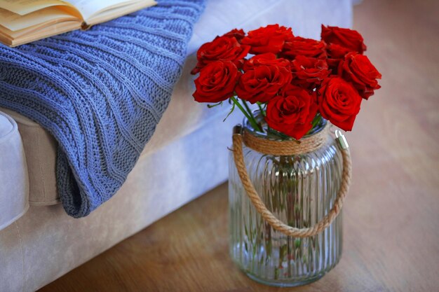 Vaso di vetro di rose rosse sul pavimento accanto al divano