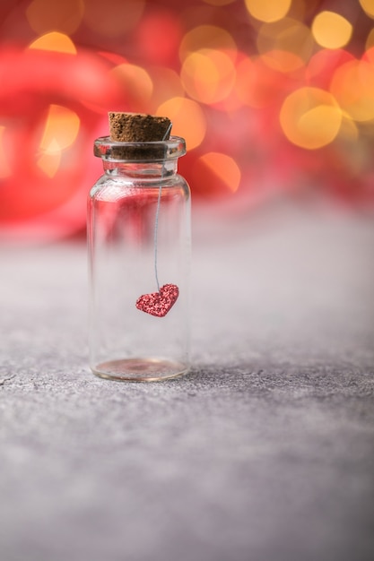 Vaso di vetro e cuore rosso su sfondo rosso. Concetto di amore nel giorno di San Valentino.