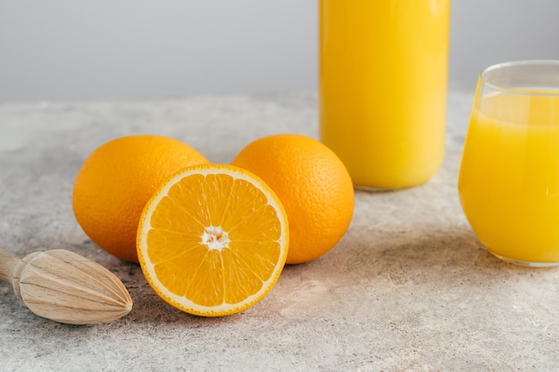 Vaso e bicchiere di succo d'arancia frutta d'arancia e spremiagrumi su sfondo bianco Metà di arancia matura Bevanda fresca con vitamine