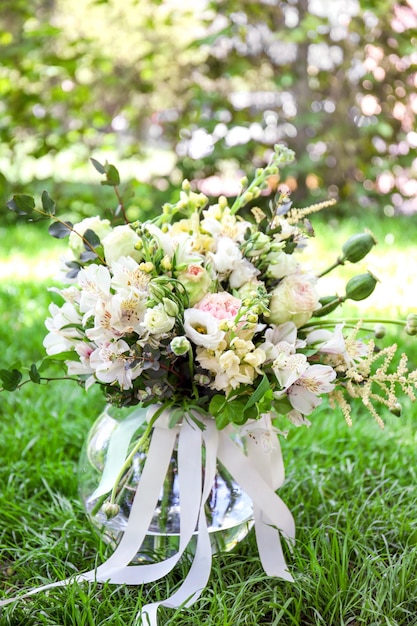 Vaso festivo con bellissimo bouquet di fiori diversi sull'erba in giardino