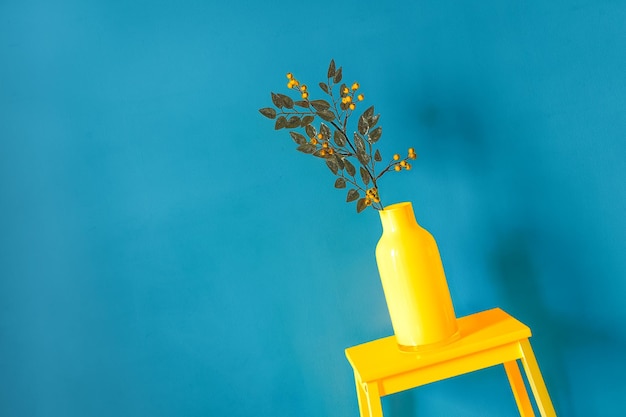 Vaso giallo di fiori su sfondo blu
